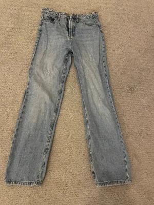Ljusblå raka jeans från Denim 1953 - Säljer ett par ljusblå jeans från Denim 1953 i storlek 36. Modellen har rak passform och klassisk femficksdesign. Jeansen är tillverkade i jeansmaterial och har hög midja. 