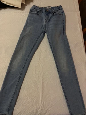 Ljusblå slim jeans Sondre 164 - Ljusblå jeans från Sondre i modellen slim fit. Klassisk femficksdesign, resår i midjan och snygga slitningar framtill. Perfekta för dig som gillar en smalare passform och vill ha ett par bekväma jeans till vardags.