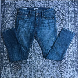 Slim Glenn jeans från Jack & Jones - Snygga blå Slim Glenn jeans från Jack & Jones med klassisk femficksdesign och orangea sömmar. Modellen har en slim passform och raka ben, tillverkade i slitstarkt bomullsmaterial. Perfekt för dig som gillar en stilren och modern look.