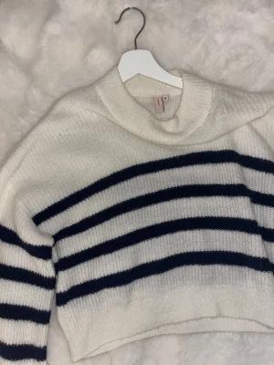 Vit och marinblå randig stickad tröja - Säljer en mysig stickad tröja från Nelly i storlek M. Tröjan är vit med marinblå horisontella ränder. Modellen är croppad med långärmade ärmar och har en loose passform. Använd 1-2 tillfällen.