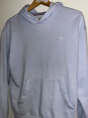 Ljusgrå hoodie från Jordan - Säljer en stilren ljusgrå hoodie från Jordan med broderad Jumpman-logga på bröstet. Tröjan har huva, magficka och är tillverkad i mjuk bomullsmix. Perfekt för chill dagar och streetwear-vibe. Långärmad och loose fit för extra komfort.
