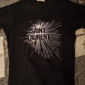Svart Saint Laurent t-shirt med tryck - Sällsynt t-shirt från Saint Laurent med coolt vitt grafiskt tryck på bröstet. Helt oanvänd, endast testad. Priset är inte hugget i sten, pm för frågor.