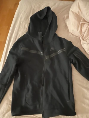 Nike tech kofta äkta  - Är svart med detaljer på framsidan och märket Nike, har också en fika på sidan av armen 