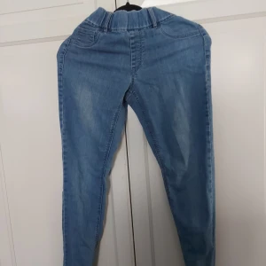 Ljusblå jeansbyxor från KappAhl - Säljer ett par ljusblå jeansbyxor från KappAhl i storlek 36. Byxorna har resår i midjan, klassiska fickor fram och bak samt en slim passform. Perfekta för en chill och avslappnad stil. Materialet är mjukt jeans och färgen är snyggt tvättad.