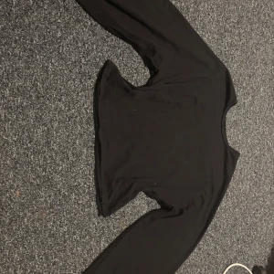 Svart croppad långärmad topp 157 - Säljer en svart croppad långärmad topp från 157 i storlek L. Toppen har rund hals och är tillverkad i mjuk bomull, perfekt att styla med jeans eller kjol. Enkel och stilren design som funkar till många olika looks.