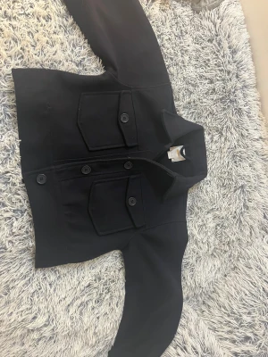 Svart overshirt från Gina Tricot - Använd 1 gång den är lite för liten så väljer o sälja den Svart overshirt från Gina Tricot med klassisk krage och stora fickor framtill med knappar. Jackan har en rak och lite boxig passform, långa ärmar och är tillverkad i ett mjukt material som känns skönt mot huden. Perfekt för lager-på-lager och enkel att styla. Bra för julklapp tips pris kan diskuteras 