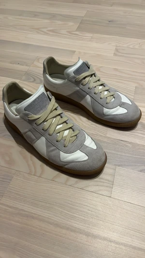 Maison Margiela sneakers grå/vit - Maison Margiela sneakers i en clean grå och vit färg, passar perfekt till dig som gillar fräscha sneakers och är snyggt i alla årstider!!