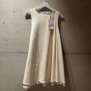 Vit kortklänning från Zara - Superfin ljus kortklänning från Zara med rund hals och ärmlös design. Klänningen är tillverkad i mjuk bomull och har två lager. Perfekt klänning till studenten eller midsommar! Har tyvärr aldrig kommit till användning men hade varit roligt om den gjorde det!