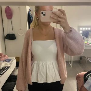 Vit peplum-linnetopp från H&M Divided - Supersöt vit linnetopp från H&M Divided med smala axelband och peplumvolang nedtill. Toppen har en rak urringning och är perfekt för varma dagar. Enkel och stilren design som är lätt att matcha med jeans eller kjol.