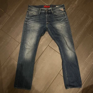 Replay Waitom jeans blå 34 - Säljer ett par Replay Waitom jeans i klassisk blå tvätt med snygga slitningar och kontrastsömmar. Modellen har raka ben, fem fickor och detaljerade bakfickor. Jeansmaterialet är slitstarkt och bekvämt.