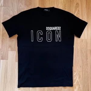 Svart DSQUARED2 ICON t-shirt - Svart t-shirt från DSQUARED2 med stor vit ICON-print på bröstet och klassisk rund hals. Snygg och stilren design som sticker ut med sitt tydliga tryck. Perfekt för dig som gillar streetwear och vill ha en statement-piece i garderoben.