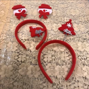 Röda juldiadem med snögubbe och gran - Två festliga röda diadem med julmotiv. Ett diadem har snögubbar med röda hattar och rosetter, det andra har röda julgranar med texten 'Merry Christmas' och snöflinga. Perfekt för julfirandet och roliga bilder!