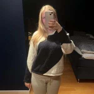 Svartvit stickad tröja med diagonal design - Säljer en stickad tröja i svart och vitt med en snygg diagonal färgblock-design. Tröjan har rund halsringning och långa ärmar. Perfekt för dig som gillar en chill och trendig look. Passformen är normal och materialet känns mjukt och skönt.