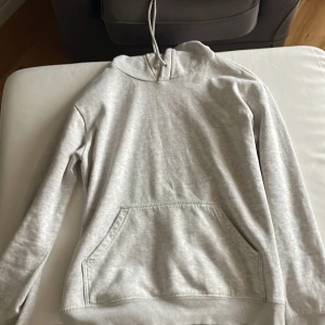 Ljusgrå hoodie från H&M XS - Säljer en ljusgrå hoodie från H&M i storlek XS. Tröjan har huva med snörning, en stor magficka och ribbade muddar vid ärmslut och nederkant. Perfekt för chill dagar och enkel att matcha med jeans eller mjukisbyxor.
