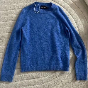 Blå stickad tröja från Pieces XS - Mysig blå stickad tröja från Pieces i storlek XS. Tröjan har rund hals, ribbade muddar vid ärmslut och nederkant samt långärmad passform. Perfekt för dig som gillar enkel och stilren design med en poppig färg.