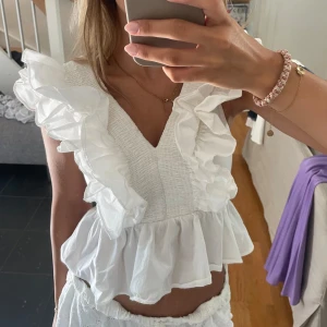 Vit topp volang  - Vit topp med volang så fin älskar!Är lite tveksam på att sälja där av priset💖Första bilden är lånad, andra är jag