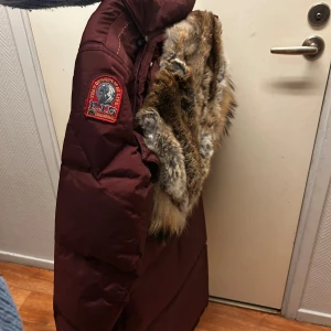 dunjacka Parajumpers XS - Säljer en lång dunjacka från Parajumpers med snyggt pälsfoder i huvan och coolt patch på ärmen. Jackan har dragkedja, flera fickor och detaljer. Perfekt för kalla vinterdagar och riktigt stilren look.  I absolut nyskick förutom någon fläck på fickan men annars är dunet pälsen å allt i toppen skick. Använd en halv vinter . Äkta med lapparna kvar 