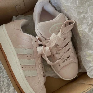 Adidas Campus ljusrosa sneakers - Adidas Campus sneakers i ljusrosa mocka med klassiska vita ränder på sidorna och vit logga. Den kostar 1440 ny