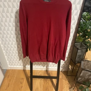 Vinröd tröja från Dressmann M - Superskön vinröd tröja från Dressmann i mjuk supima bomull. Klassisk rund hals och långa ärmar, perfekt för dig som gillar enkel och stilren look. Ribbad kant vid hals, ärmslut och nederkant. Passar dig som vill ha en normal passform.