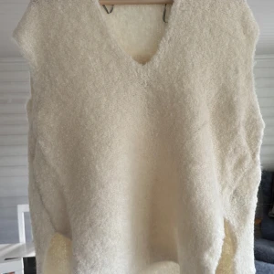 Arket stickad slipover i stl S ull alpacka helt ny - Säljer en fluffig och mjuk vit väst från Arket i exklusiv ullblandning. Västen har en snygg v-ringad hals och är ärmlös med en loose passform. Perfekt att styla över en skjorta eller t-shirt för en chill look.