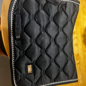 Schabrak  - Elegant marinblått hopp-schabrak från Equestrian Stockholm i full storlek. Materialet är i fint skick, endast mindre ytliga repor på metallbrickan. Perfekt för dig som vill ha stil och komfort till din häst.💗säljer då jag slutat i ridning, nypris 900kr