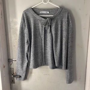 Grå kofta  - Mysig gråmelerad kofta från 157 i storlek XL. Tröjan har långa ärmar och en rund halsringning med snyggt knyt framtill. Materialet är mjukt och känns skönt mot huden, perfekt för kyliga dagar. Enkel och stilren design som funkar till många olika looks. Perfekt till höst&vinter!