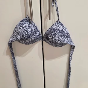 Leopardmönstrad bikini från Andy by Frank Dandy - Snygg bikiniöverdel i svartvitt leopardmönster från Andy by Frank Dandy. Modellen har trekantskupor och knytband i nacken och ryggen för perfekt passform. Tillverkad i stretchig polyester och elastan, perfekt för strandhäng eller poolparty.