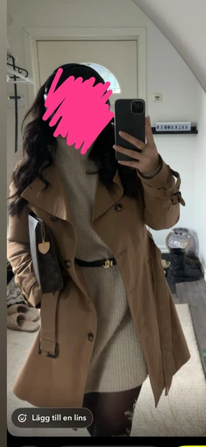 Beige trenchcoat med bälte - Snygg brun trenchcoat med klassisk krage och knappar framtill. Jackan har bälte i midjan och spännen vid ärmsluten för extra stil. Perfekt för lager-på-lager och ger en clean look till alla outfits.