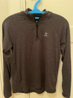 Mörkgrå träningströja  - Sportig mörkgrå långärmad träningströja från SOC med half zip framtill och liten logga på bröstet. Passar 11-12Y.