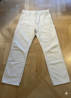Vita Carhartt Double Knee Pants 30x32 - Säljer ett par vita Carhartt Work In Progress Double Knee Pants med raka ben Byxorna har flera praktiska fickor, bälteshällor och Carhartt-logga på bakfickan. Priset är inte fast så bjud gärna.