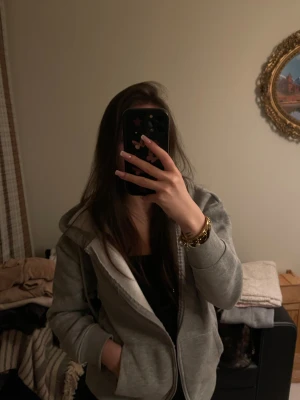 Grå hoodie med dragkedja och huva - Säljer en grå kofta med dragkedja och stor huva eftersom den är för kort på armarna på mig och aldrig använt. Jackan har ribbade muddar, fickor på sidorna och är i mjukt bomullsmaterial. Perfekt för dig som gillar en enkel och clean look. Passar dig som vill ha en bekväm och stilren vardagsjacka. 