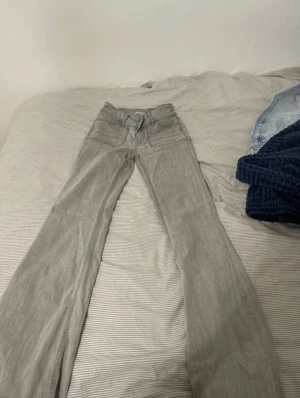 Grå bootcut jeans - Snygga grå jeans med bootcut passform och klassisk femficksdesign. Byxorna har dragkedja och knapp framtill samt bälteshällor. Perfekta för allt. De är trendiga och lågmidjade och sitter som en smäck 