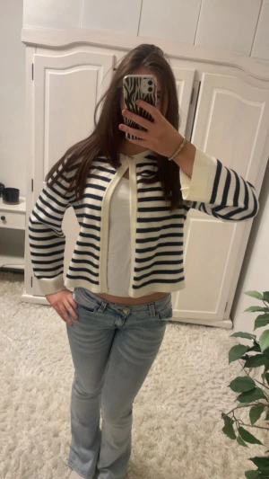 Randig kofta i vitt och marinblått - Säljer en söt kofta med marinblå och vita ränder. Koftan, har lång ärm och knäpps med en liten knapp upptill. Mjukt stickat material och breda muddar vid ärmslut och nederkant. Skit skön material, har använt bara en gång!