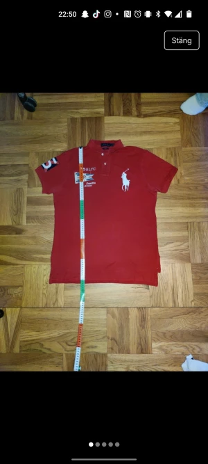 Big pony Ralph Lauren pike - En snygg röd Ralph Lauren Polo pike med big pony i fint skick. Passar fint på de allra flesta personer!