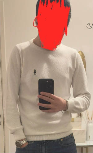 Vit stickad tröja från Polo Ralph Lauren - Vit stickad tröja från Polo Ralph Lauren med rund hals och klassisk logga broderad på bröstet. Tröjan har långärmade ribbade muddar och en diskret struktur i materialet som ger en snygg look. Sparsamt använd och passar lite mer som S även fast den e M