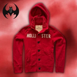 Röd Hollister Kofta / Hoodie - Röd kofta från Hollister med knappar och broderad vit text på bröstet | Size S | Längd: 64cm Axelbredd: 42cm Armlängd: 69cm | Passar mellan för 164-178 cm