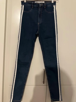 Blå skinny jeans med vita ränder Zara - storlek 36 - Snygga blå jeans från Zara Trafaluc Denim Collection i skinny fit med vita ränder längs sidorna. Klassisk femficksmodell, hög midja och dragkedja med knapp. Jeansen är gjorda i stretchigt denim.