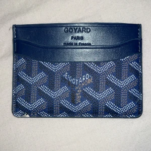 Blå HM plånbok med mönster - Snygg blå plånbok från HM med klassiskt grafiskt mönster i vitt och brunt. Plånboken har flera fack för kort och är tillverkad i skinn med lyxig känsla. Perfekt för dig som vill ha något stilrent och exklusivt i fickan.