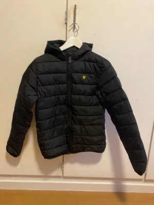 Lyle and scott jacka storlek 11-12 år - Svart pufferjacka till barn storlek 11-12 år från Lyle & Scott med gul logga på bröstet. Köpt för ca 1 år sen för 1100kr, nyskick endast använd ett fåtal gånger. 