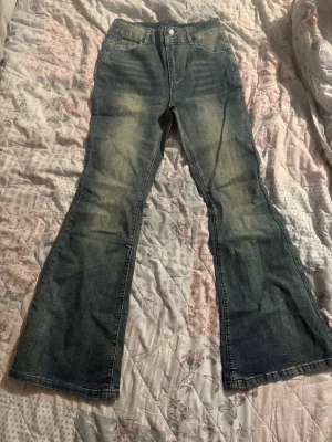 Blå bootcut jeans med slitningar - Snygga blå jeans med bootcut passform och lätt slitna detaljer framtill. Klassisk femficksmodell med knapp och dragkedja i midjan. Jeansen har en cool tvättad look och är tillverkade i jeansmaterial som ger en skön känsla.