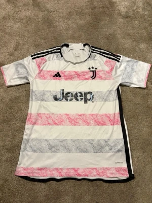 Juventus randig fotbollströja Adidas - Juventus fotbollströja från Adidas med breda ränder i vitt, rosa och grått. Tröjan har svarta detaljer på axlarna och ett Juventus-emblem med tre stjärnor på bröstet. Jeep-logga framtill och klassisk rund hals. Materialet är lätt polyester. Skicka pm vid funderingar.😁🙌🏻