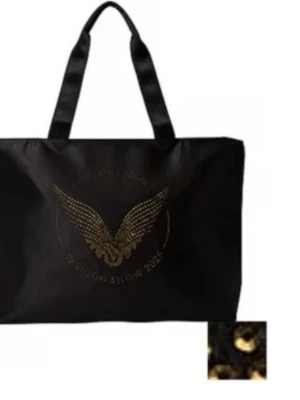 Victoria’s Secret Fashion Show tote – oanvänd - Svart Victoria’s Secret tote bag från Fashion Show i USA 🤍 Fick den i samband med köp men har aldrig använt den – helt ny med prislapp kvar.  👜 Rymlig tygväska ✨ Snygg guldfärgad logga/nitar 🖤 Perfekt till skola, jobb, shopping eller strand 🎁 Originalpris ca $60 (ca 650 kr)  Skickas snabbt 💌 eller möts upp. Pris kan diskuteras vid snabb affär. 