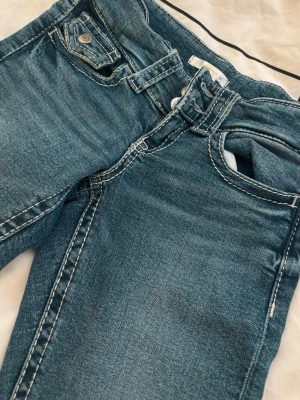 Blå bootcut jeans från Gina Tricot - Snygga blå bootcut jeans från Gina Tricot. Jeansen har silverfärgade knappar där bak och låg midja. Inga defekter. Säljer då de tyvärr blivit försmå. Passar till allt. Skriv vid frågor, svarar & postar snabbt💋🙏🏼