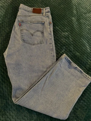 Levi's Premium ljusblå jeans straight storlek 30 - Ljusblå Levi's Premium jeans med klassisk femficksdesign och rakt snitt. Jeansen har hög midja och är tillverkade i slitstark bomullsdenim. Snygga kontrastsömmar och ikonisk röd Levi's-tag på bakfickan. Perfekt för dig som gillar en clean och tidlös look.