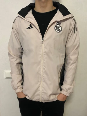 Real Madrid vindjacka  - Säljer en beige Real Madrid vindjacka. Har använts fåtal gånger och är inprincip i nyskick utan defekter. Skriv för minsta fundering 😊