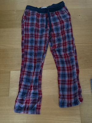 Röd-rutiga mjukisbyxor från Kappahl - Säljer ett par mjuka och sköna mjukisbyxor från Kappahl i storlek S. Byxorna har ett rött och blått rutigt mönster, elastisk midja med snörning och är perfekta för chill hemma. Materialet är bomull och de har en loose passform. 100% Bomull