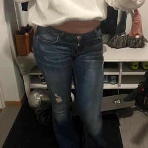 Blå bootcut jeans med slitningar - Säljer dessa snygga lågmidjade jeans med slitningar, jeansen kommer från gina men finns inte längre kvar att köpa.