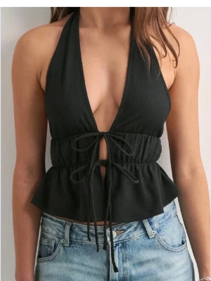 Svart omlott halterneck topp - Säljer en svart omlott topp från nelly, helt oanvänd