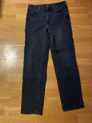 Svarta jeansbyxor från LEE W30 L33 - Snygga svarta jeansbyxor från LEE i modellen Carol. Klassisk femficksdesign med raka ben och normal passform. Materialet är mjukt och slitstarkt jeans, perfekt för dig som gillar enkel och stilren look.