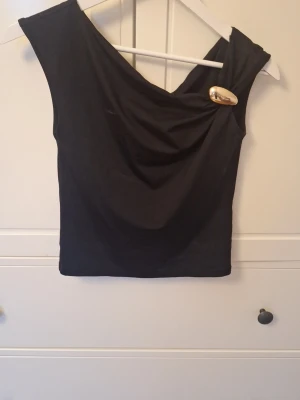 Topp med guldig metal detalj - Jättefin svart topp från gina, passar s-xs